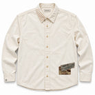 An off-white long-sleeve button-up shirt by Para Daiza, featuring a unique patterned collar with sashiko, a camouflage print pocket patch on the lower right front, and matching camouflage accents on the button placket.