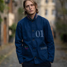 Person wearing a blue PARA-DAIZA atelier jacket with '01' on it, standing outdoors in Stockbridge.