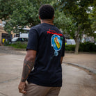 Person wearing a paradzia black t-shirt with a colorful graphic on the back, standing outdoors.
