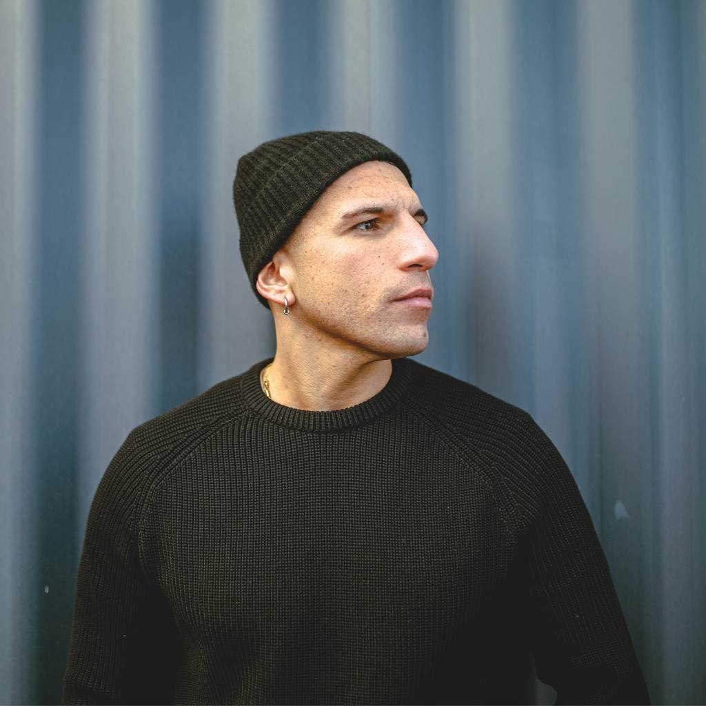 Man wearing a paradaiza black knit against a gray background