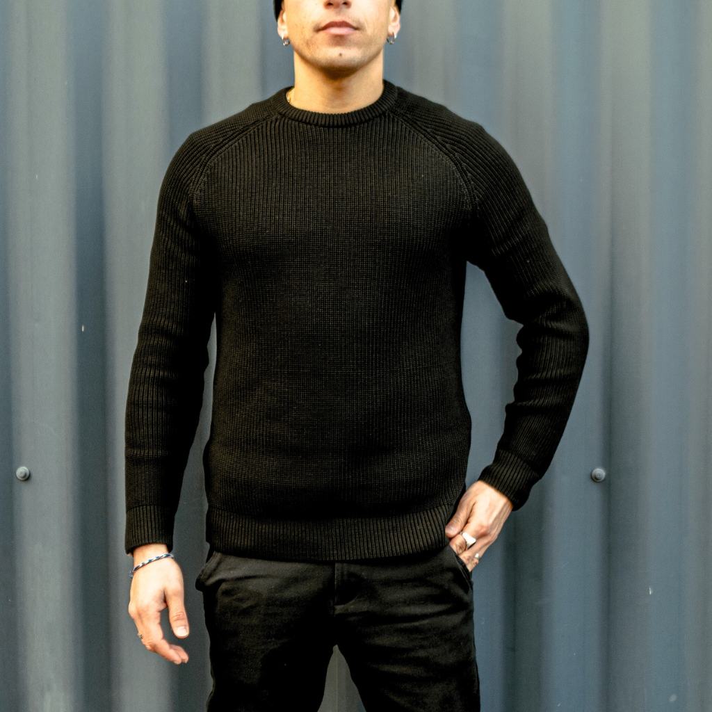 Man wearing a paradaiza black knit against a gray background