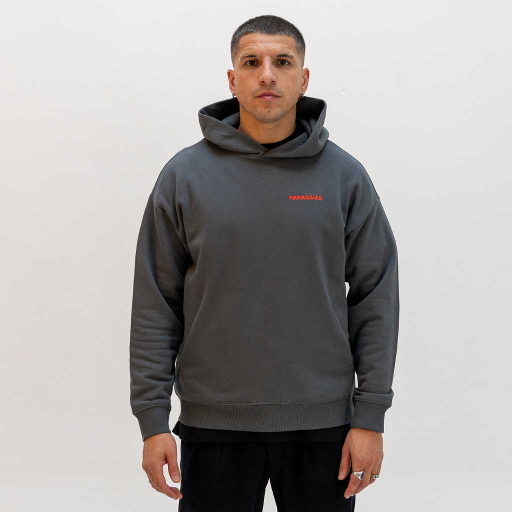 Man wearing a grey paradaiza hoodie with a red logo on a white background