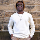 Man wearing a ivory paradaiza sweater and sunglasses against a stone wall
