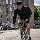 model wears paradaiza wind runner jacket and  cap on a fixed gear bike 