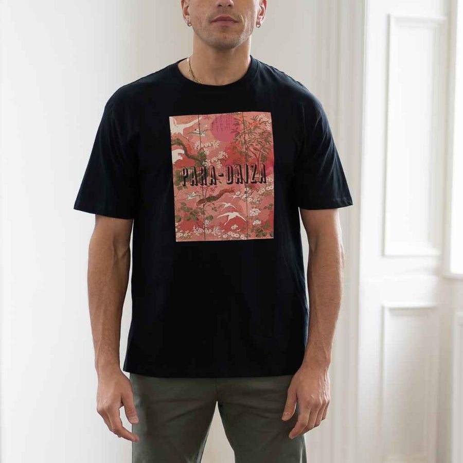 A person wearing a paradazia black crew neck t-shirt with a graphic design in the center that includes the text 'BIRDS'.