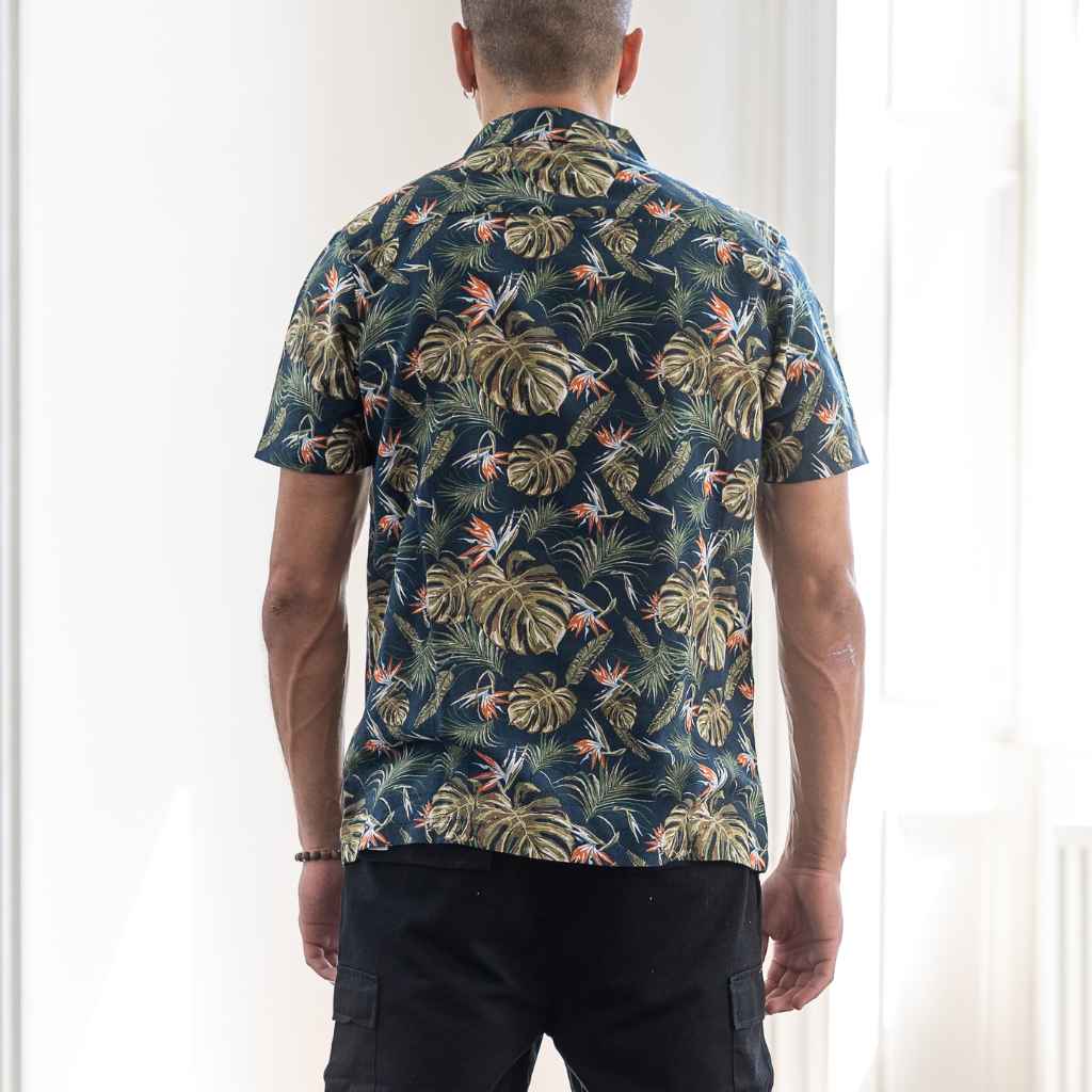 model wears paradaiza Paradise Print Shirt is made from a blend of 62% linen and 38% organic cotton, creating a lightweight and breathable fabric. The slim/regular fit with a classic bowling neck and self coloured button