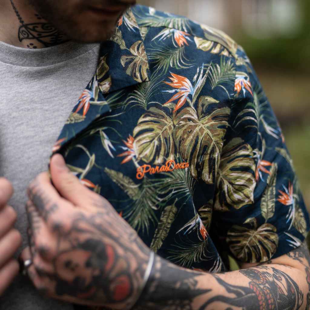 model wears paradaiza Paradise Print Shirt is made from a blend of 62% linen and 38% organic cotton, creating a lightweight and breathable fabric. The slim/regular fit with a classic bowling neck and self coloured button