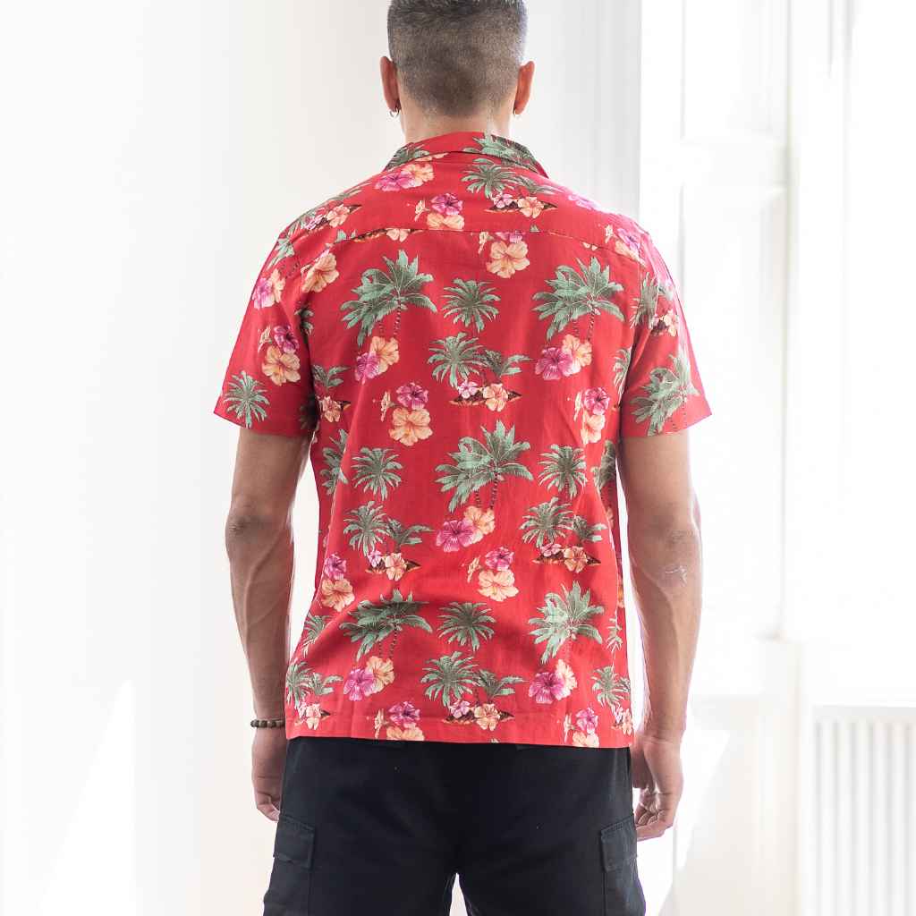 Model wears red Paradise Print Shirt is made from a blend of 62% linen and 38% organic cotton, creating a lightweight and breathable fabric. The slim/regular fit and classic bowling neck with self coloured buttons.