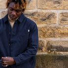 Person wearing a navy Paradaiza worker jacket against a stone wall