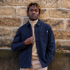 model wearing a navy Paradaiza worker jacket against a stone wall