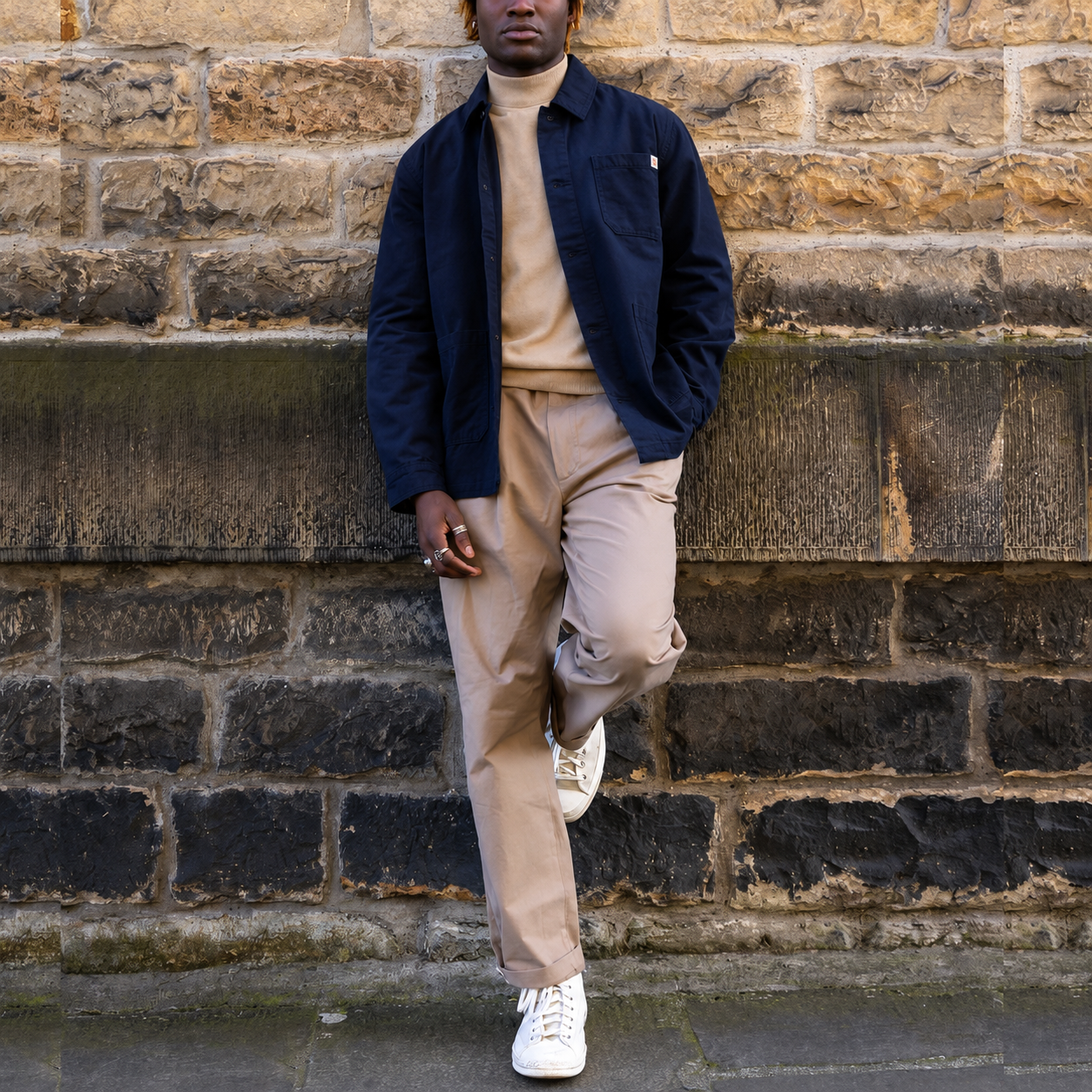 model wearing a navy Paradaiza worker jacket against a stone wall