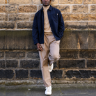 model wearing a navy Paradaiza worker jacket against a stone wall