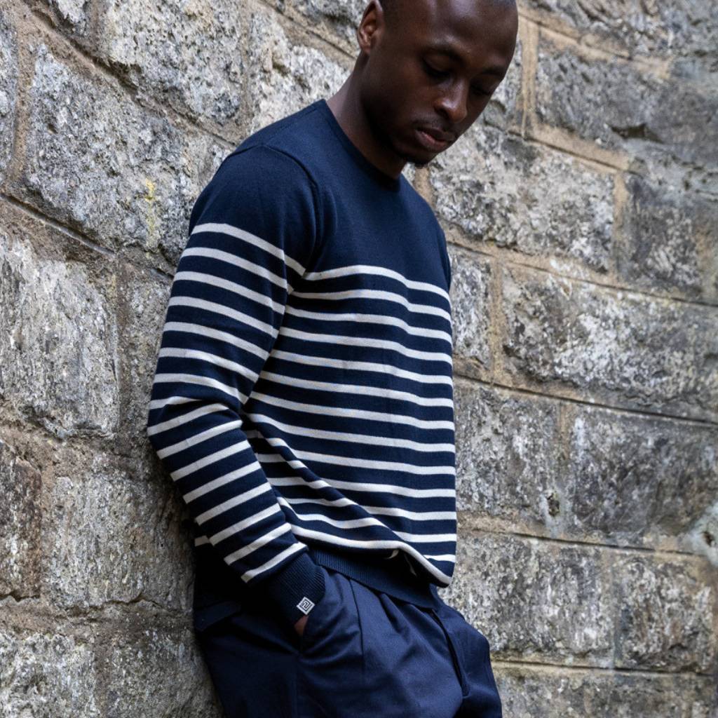 Man wearing a navy and white striped paradaiza sweater against a stone wall.