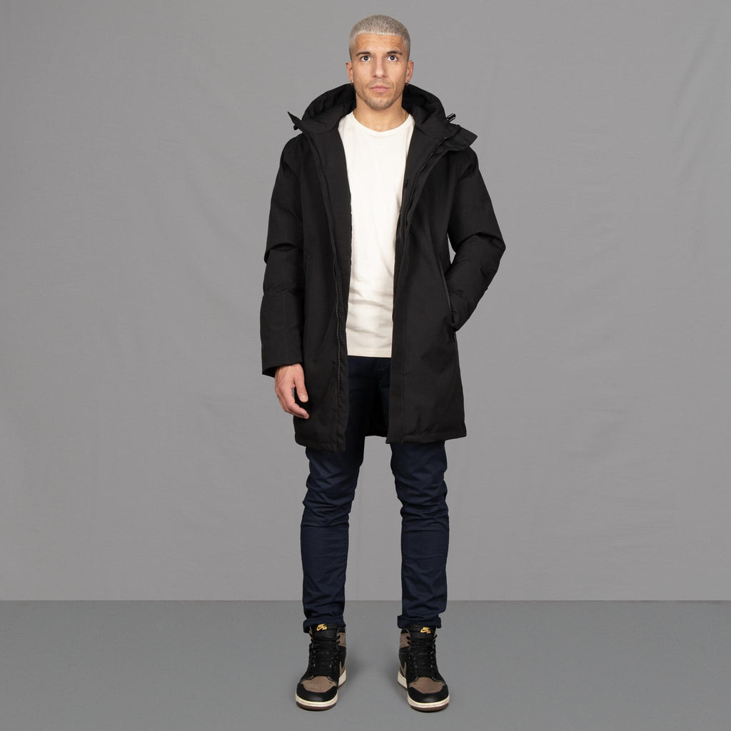 Model wears Para-Daiza Black padded parka superflex chino, off-white tee, and Nike trainers. 