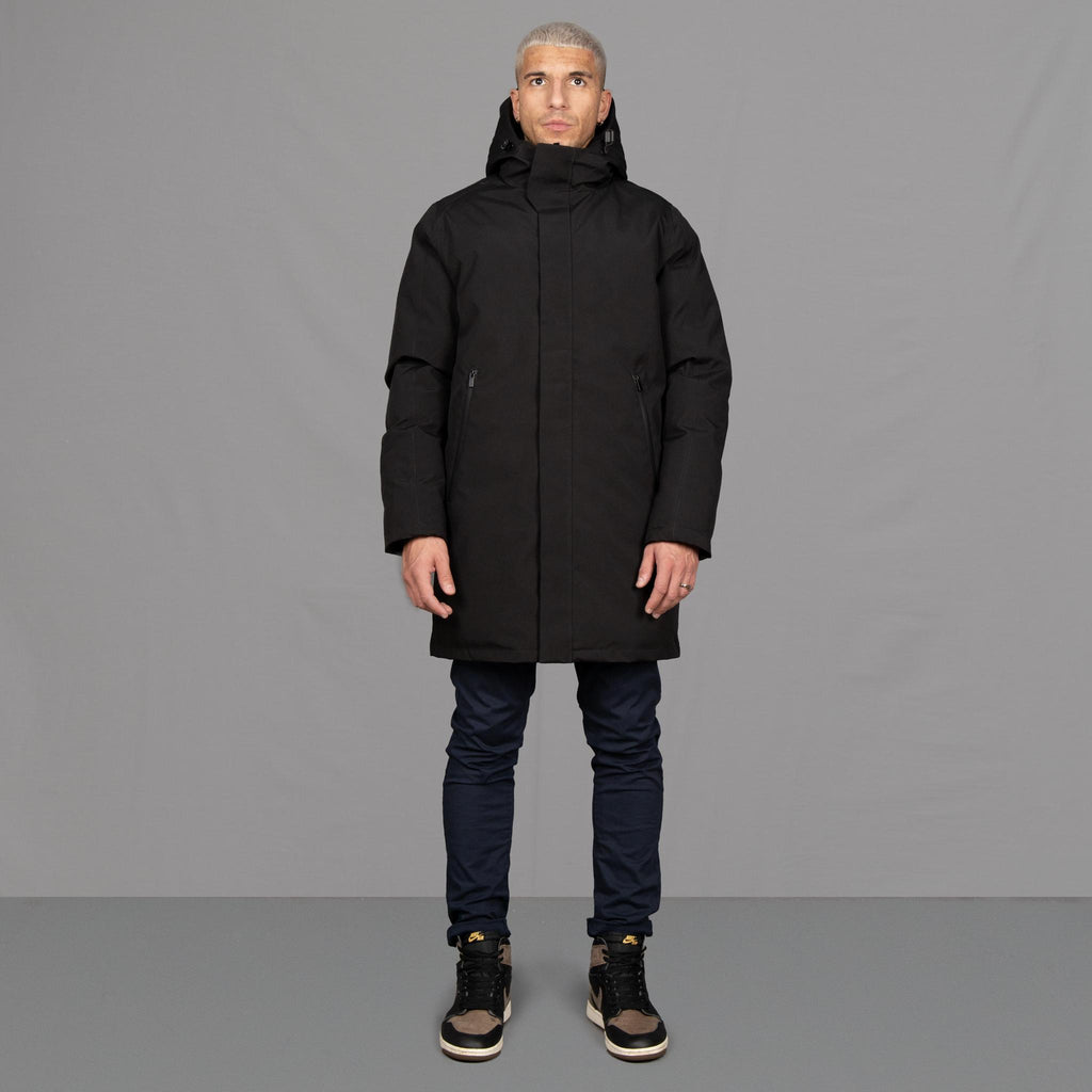 Model wears Para-Daiza Black padded parka superflex chino, off-white tee, and Nike trainers. 