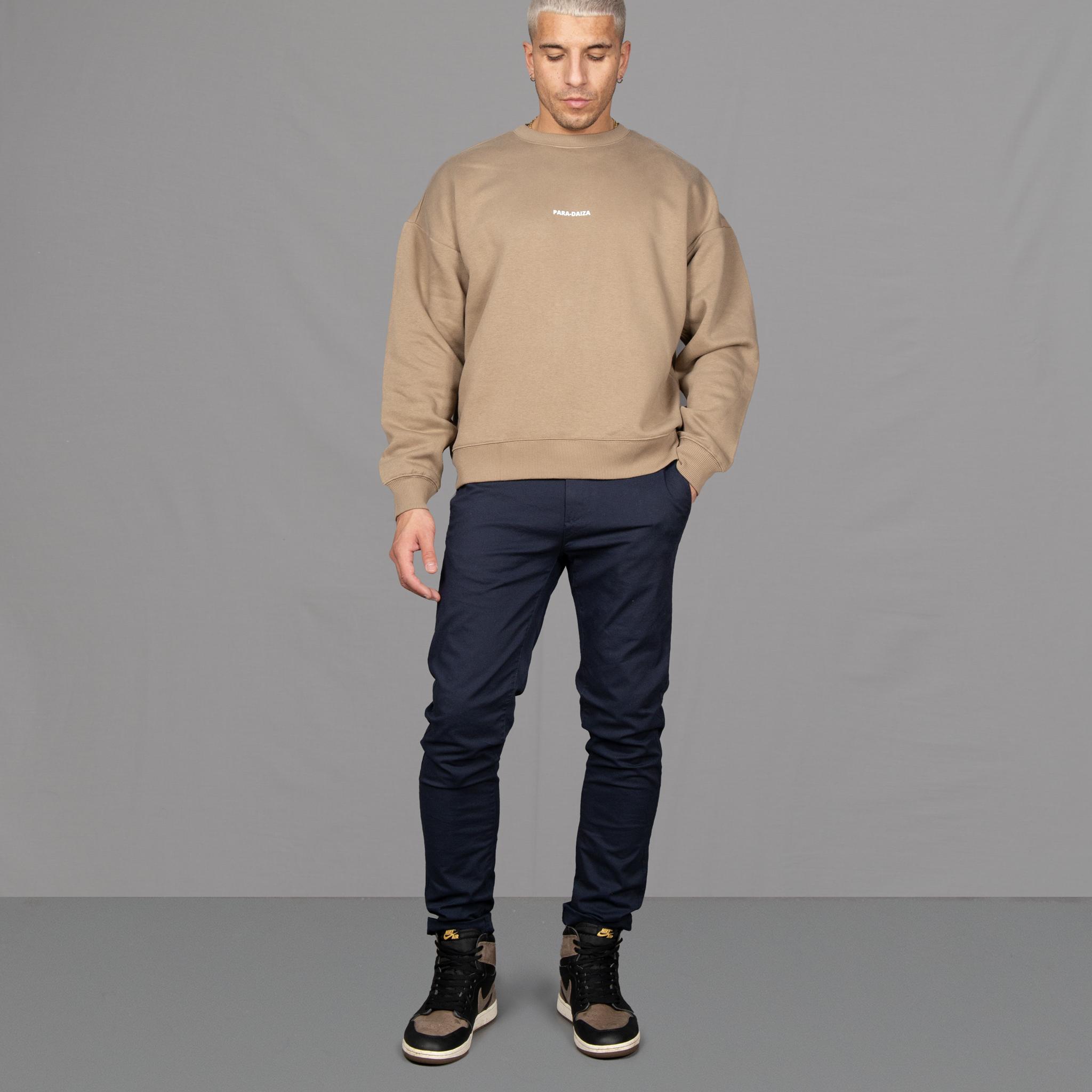 Model wears Para-Daiza Oversized Tan Crew neck sweatshirt  superflex chino, and Nike trainers. 