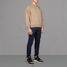 Model wears Para-Daiza Oversized Tan Crew neck sweatshirt superflex chino, and Nike trainers.