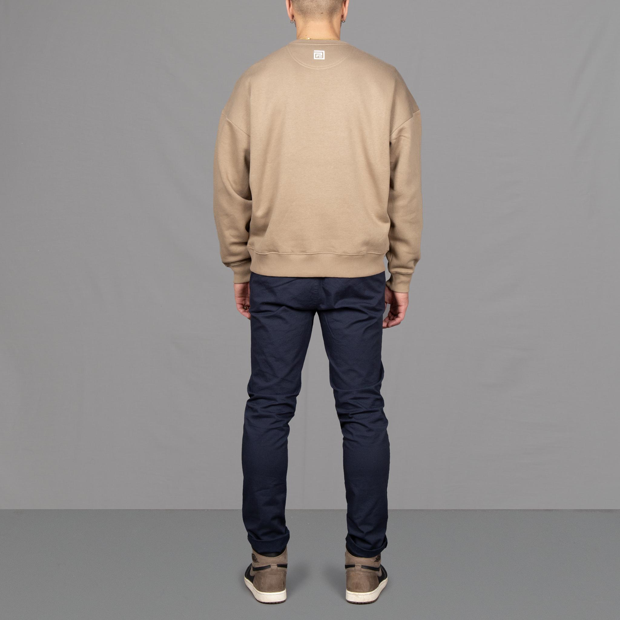 Model wears Para-Daiza Oversized Tan Crew neck sweatshirt superflex chino, and Nike trainers.