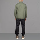 Model wears Para-Daiza Olive worker jacket , off-white tee, pinch chino and Nike trainers.