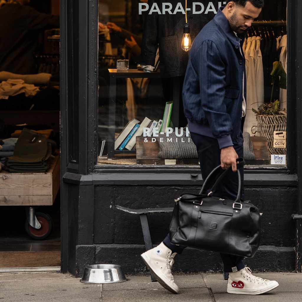 Man holding a  paradaiza black leather weekend bag