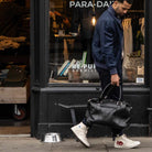 Man holding a  paradaiza black leather weekend bag