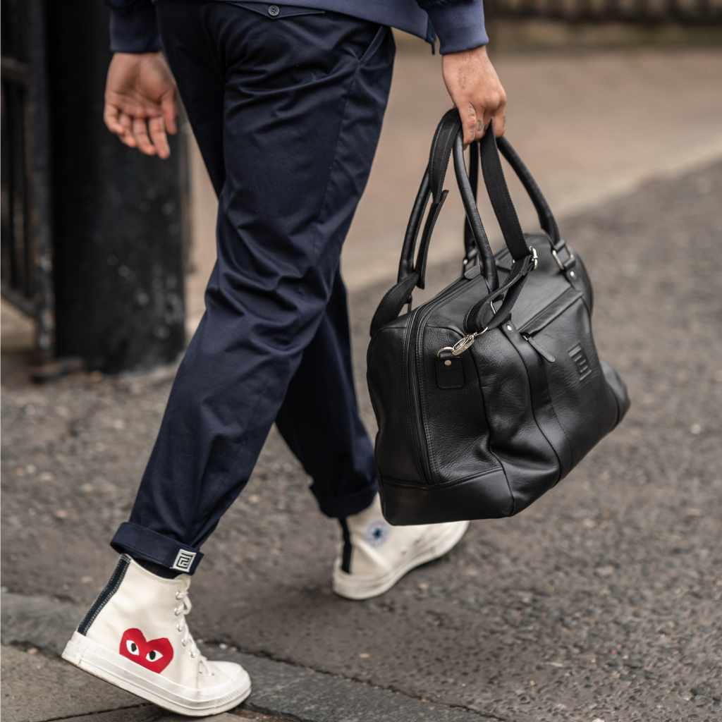 Man holding a  paradaiza black leather weekend bag