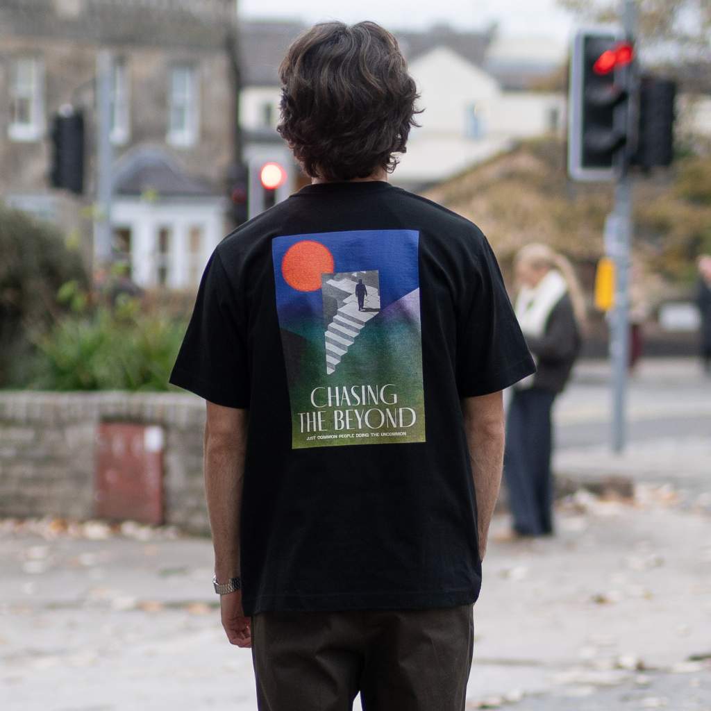 Black t-shirt with 'Chasing the Beyond' graphic design on a textured gray background