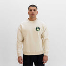 Man wearing a beige paradaiza sweatshirt with a logo on a white background