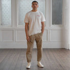 Person wearing a white t-shirt with a graphic design and 'Paradaiza' text, standing in a room with wooden flooring and white paneled walls.
