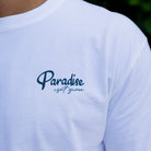 White t-shirt with 'Paradise isn't given' text on a person wearing it.