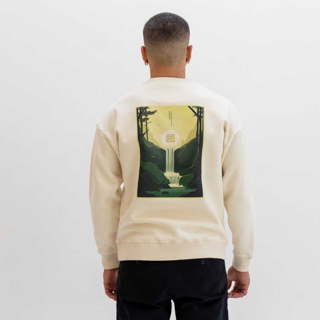 Person wearing a beige paradaiza sweat with a graphic design on the back against a white background