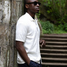 paradaiza white textured shirt and dark pants against a stone wall.