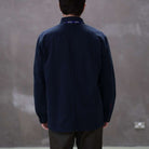 Model wearing a  paradaiza dark blue worker jacket with patterned accents and sashiko stitching  in a studio.
