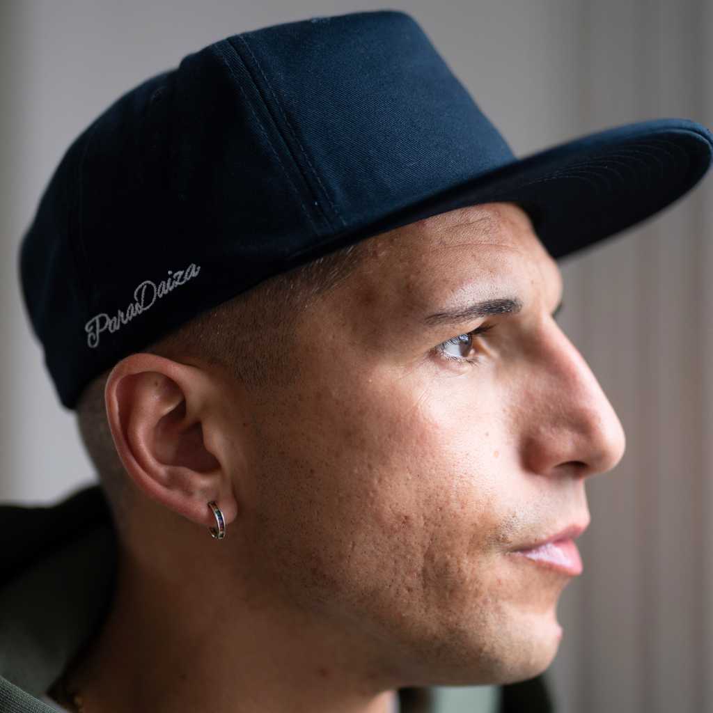 Man wearing a navy cap with 'Paradaiza' logo, looking to the side.