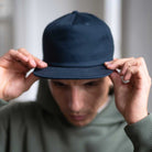 Person holding a navy blue  paradaiza cap in front of their face