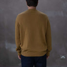 Man wearing a paradaiza mustard yellow sweater against a grey background
