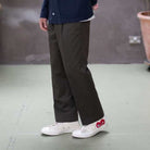 Person wearing paradaiza khaki chino pants and white sneakers with red accents on a plain floor.