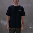 Man wearing a black t-shirt with a logo against a gray background