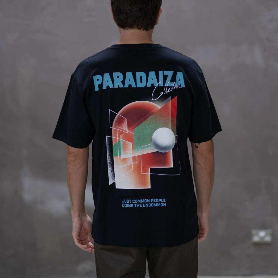 Person wearing a black t-shirt with 'Paradaiza' branding and colorful design on the back against a gray background