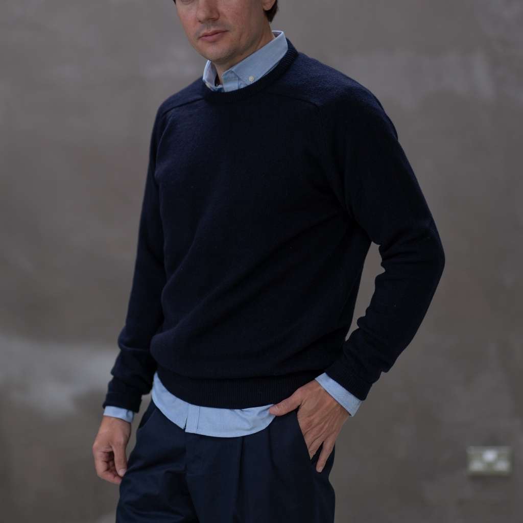 Man wearing a paradaiza navy sweater over a light blue shirt with a plain background