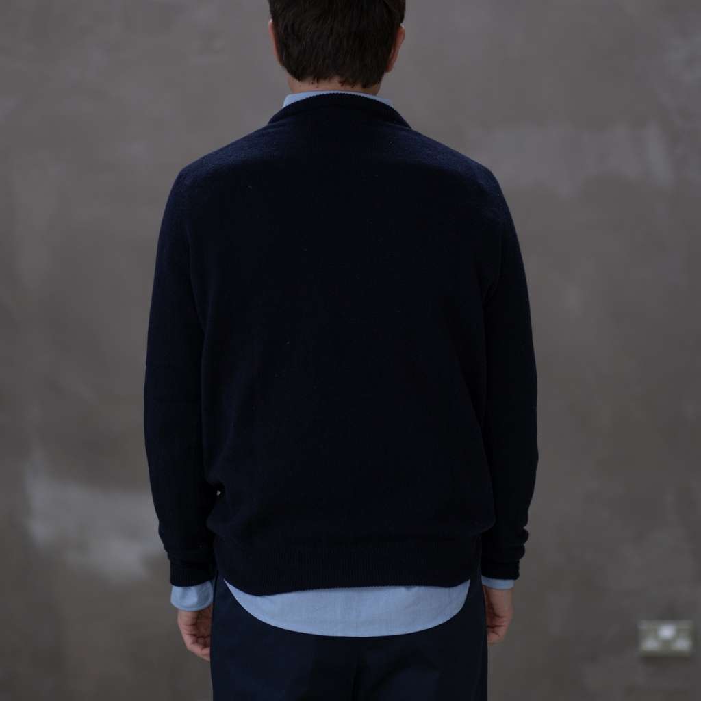 Man wearing a paradaiza navy sweater over a light blue shirt with a plain background