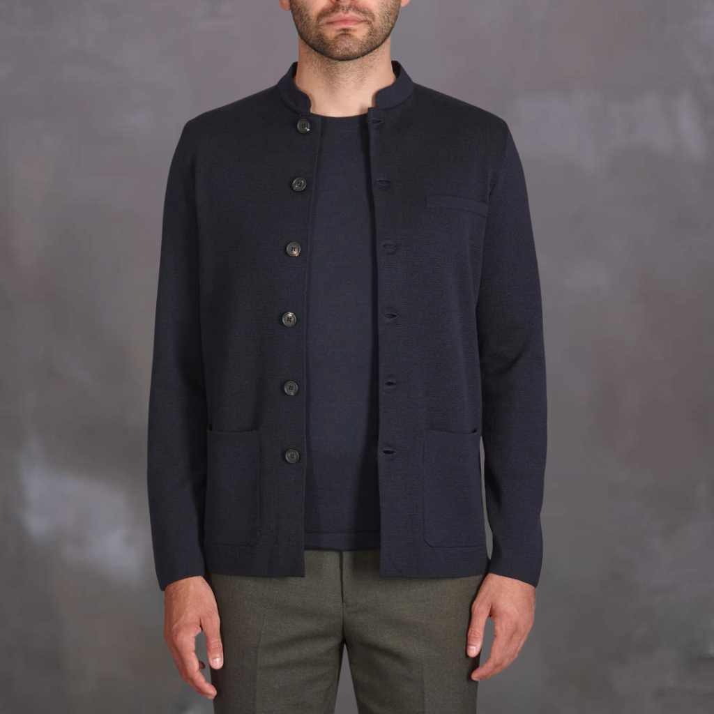 Man wearing a  paradaiza dark blue jacket against a gray background