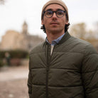 Man wearing a paradaiza khaki jacket and beige beanie standing outdoors with a blurred background
