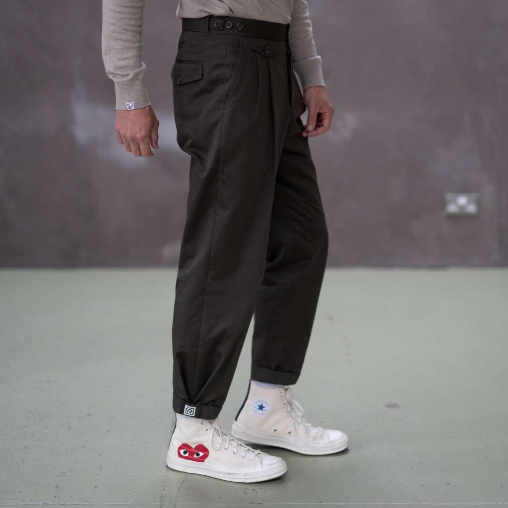 Person wearing paradaiza pinch chinos pants and white sneakers with red and blue designs on a plain background