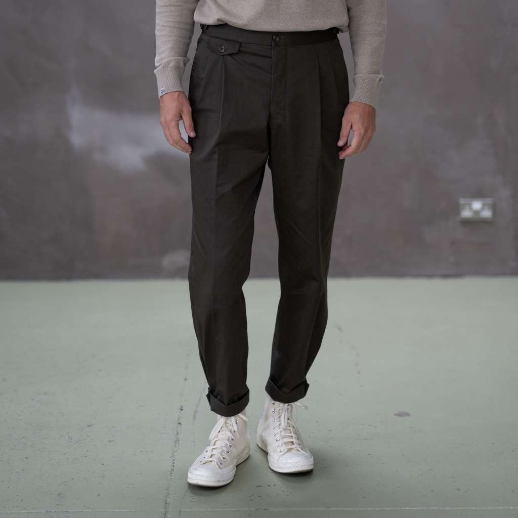 Person wearing paradaiza pinch chinos pants and white sneakers with red and blue designs on a plain background