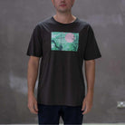 Person wearing a  paradiaiza black t-shirt with a colorful graphic on a gray background