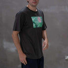 Person wearing a  paradiaiza black t-shirt with a colorful graphic on a gray background