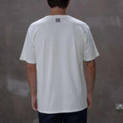 Person wearing a  paradaiza white t-shirt with a colorful graphic design on a gray background