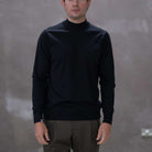 Model wearing a  paradaiza black turtleneck sweater against a gray background