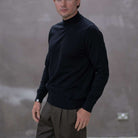 Model wearing a  paradaiza black turtleneck sweater against a gray background